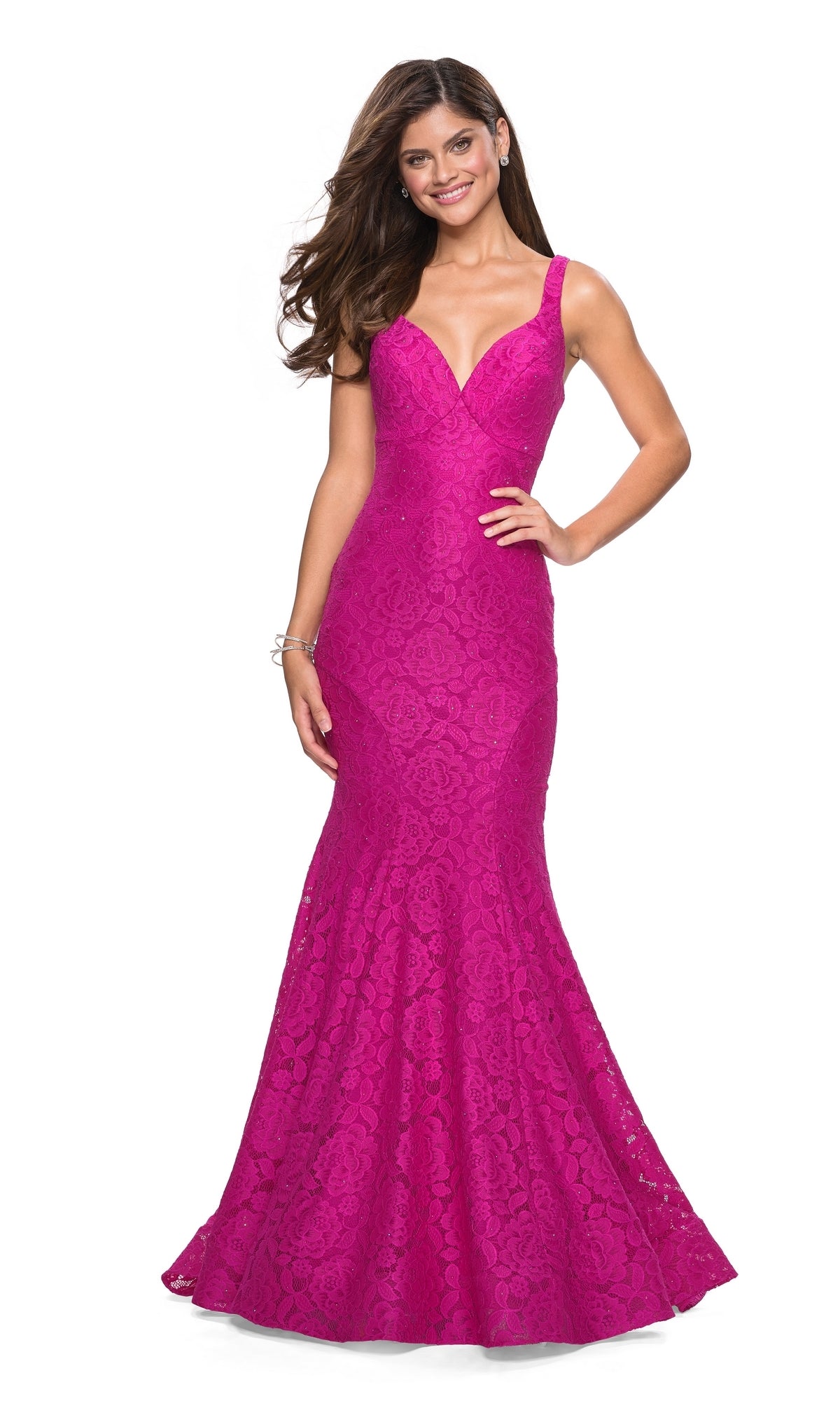 Woman in the La Femme 27623 Open-Back Lace Mermaid Prom Dress, a fitted sleeveless magenta gown with a flared hem, smiles while standing against a white background.